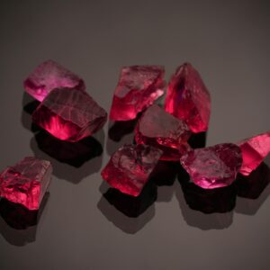 Close-up photo of vibrant red gemstones on a shiny black surface, showcasing brilliance.